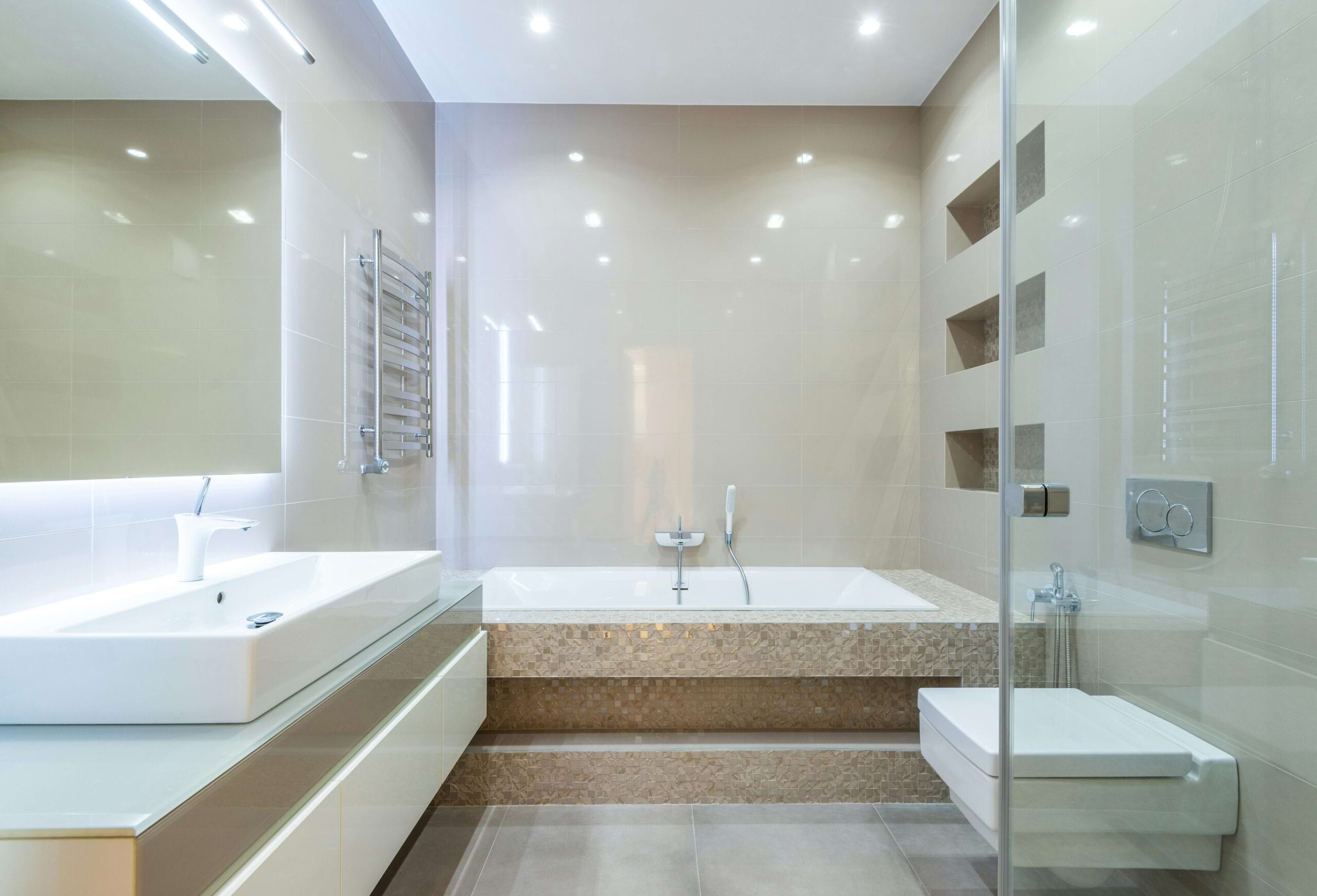Moderne Badezimmeransicht mit Badewanne, Waschbecken, Handtuchheizkörper und hellen Fliesen.