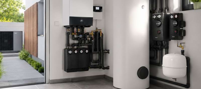 Moderne Heizungsanlage mit verschiedenen Wärmepumpen- und Sanitärkomponenten in einem hellen Raum.