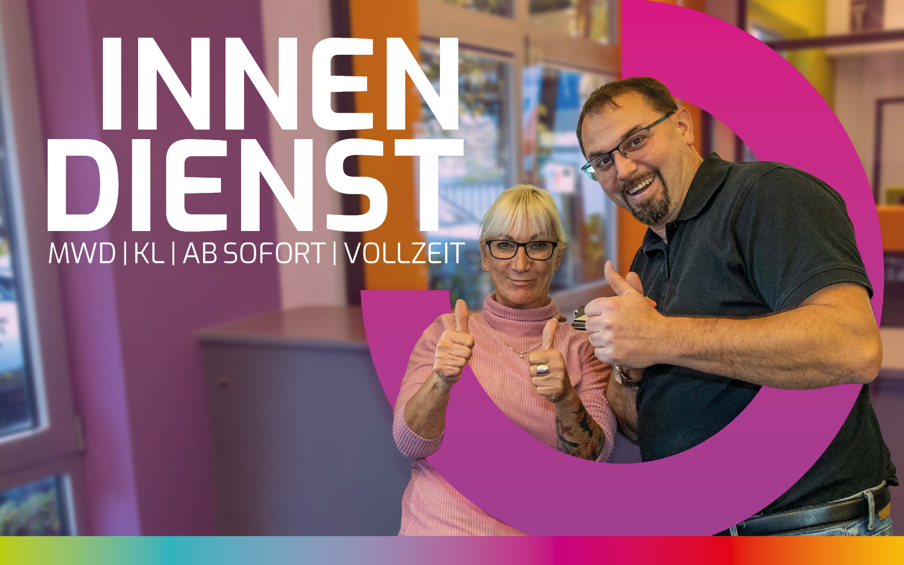 Zwei Personen stehen in einem bunten Räumen, zeigen Daumen hoch. Im Hintergrund sind Fenster und farbige Wände sichtbar.